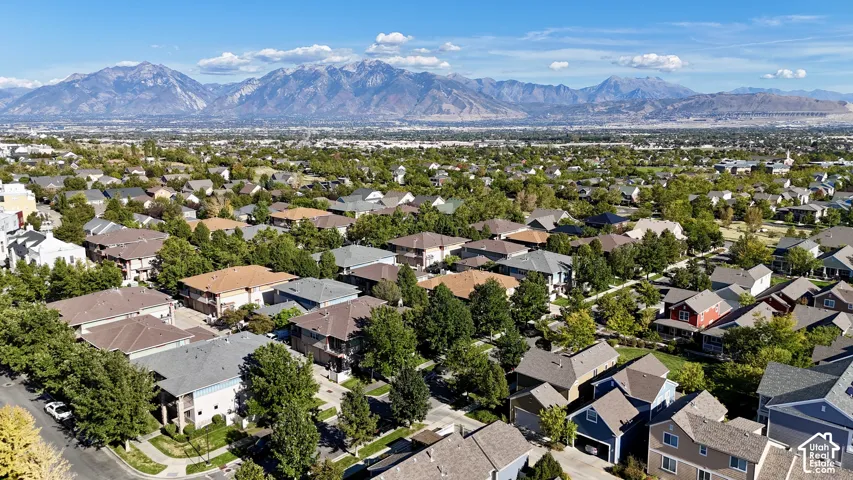 Expansive residential area with numerous detached properties, abundant mature trees, and mountainous terrain in the background