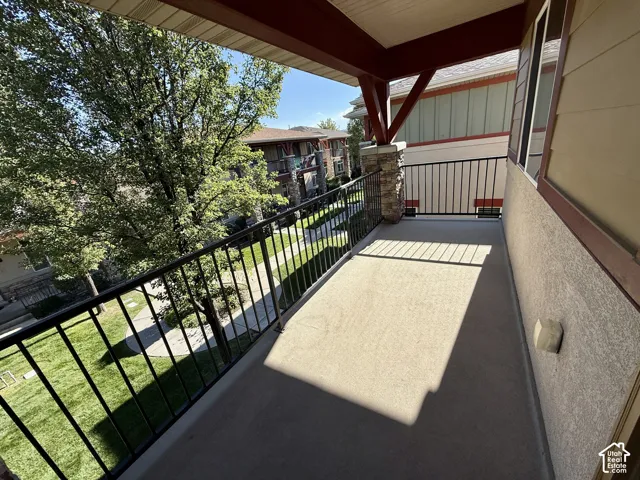 Private balcony featuring a concrete surface, black metal railing, and a stone-clad pillar