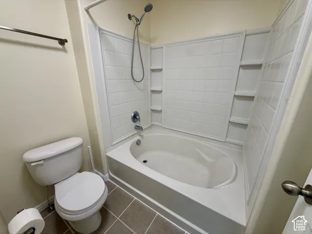 White fiberglass tub and shower combination with a curved basin and built-in shelving, complemented by a chrome showerhead and faucet