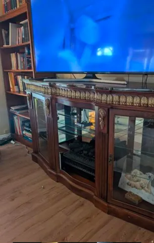Wood-finish flooring with a multi-paneled entertainment console featuring glass-front doors