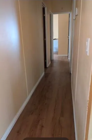Hallway featuring wood-finish flooring and light-toned wall finishes