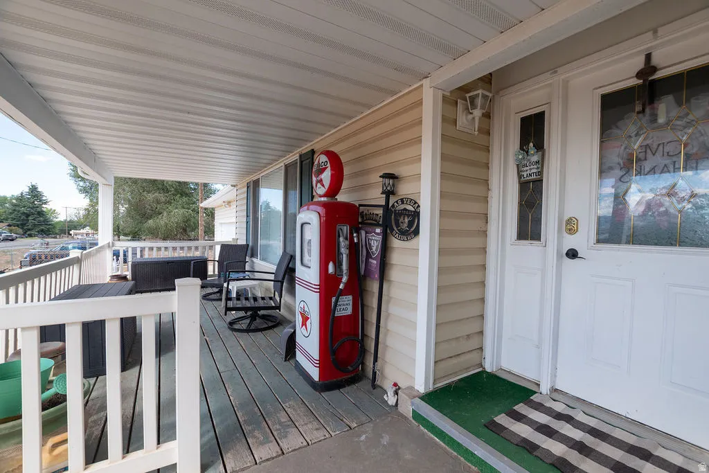 Covered porch with wood-finish decking, white railings, and siding exterior