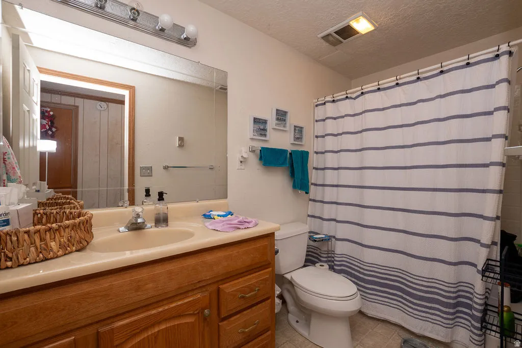 Single vanity with wood-finish cabinetry, integrated sink, and wall-mounted light fixture