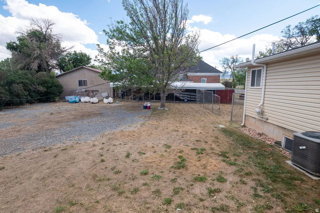 Spacious gravel driveway and expansive yard area with mature trees