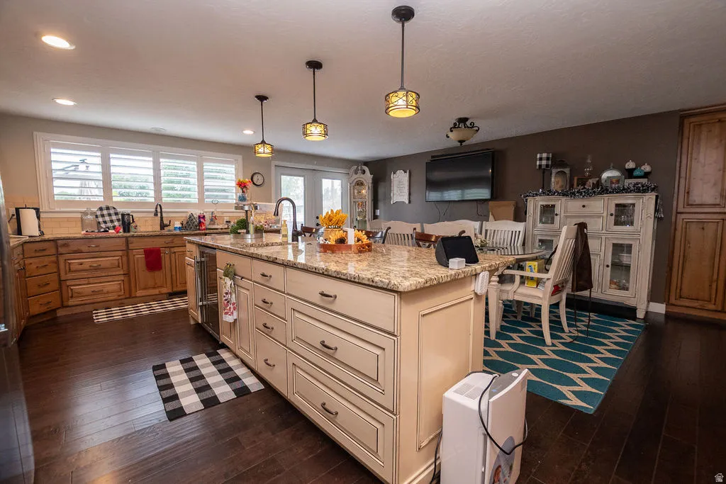 Kitchen featuring a central island with granite countertop, wood-finish flooring, recessed lighting, and pendant light fixtures
