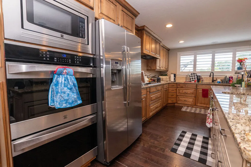 Stainless steel appliance suite, wood-finish flooring, wood cabinetry, granite countertops, and recessed lighting