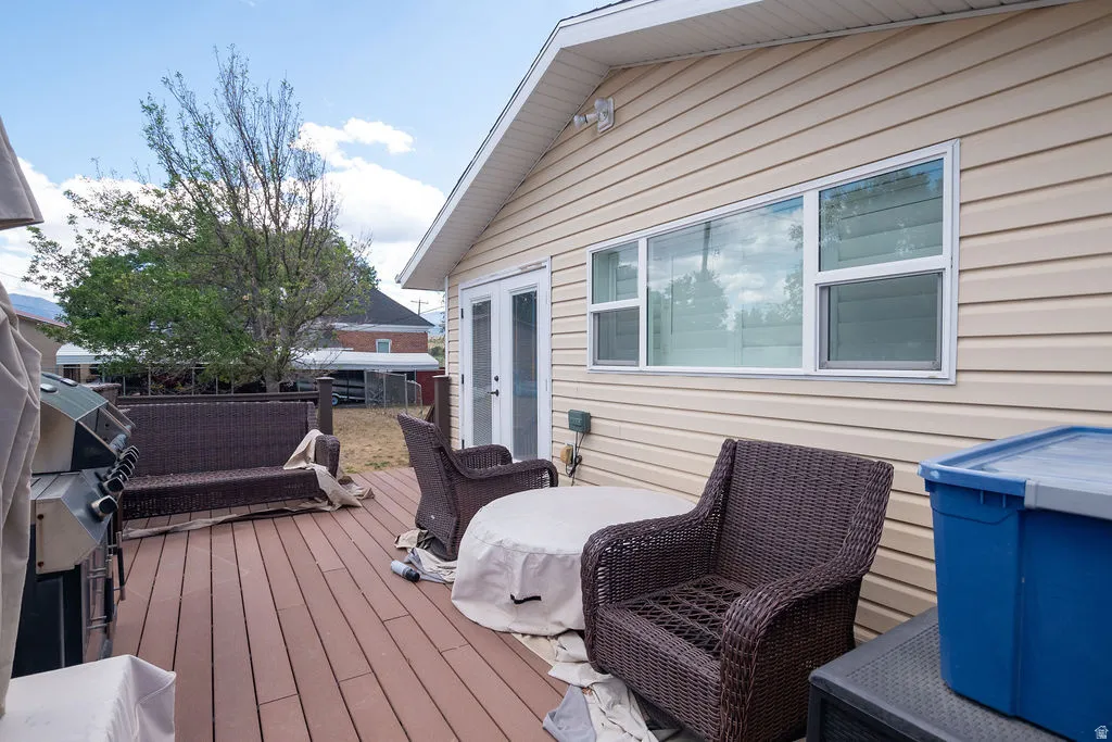 Spacious outdoor deck featuring wood-finish flooring, light-colored siding, and white-framed windows