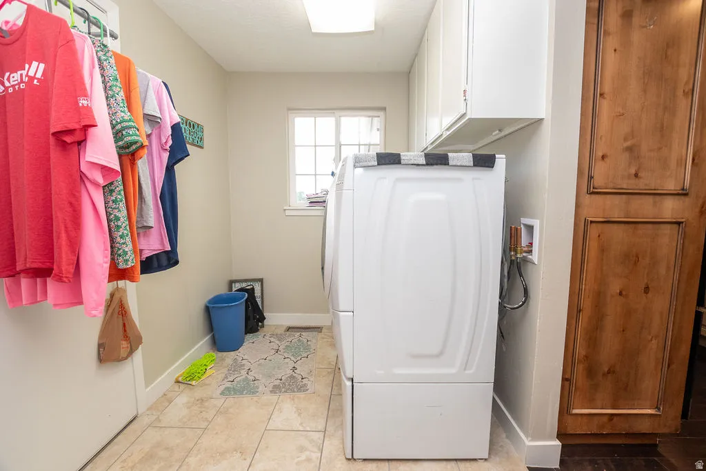 Laundry area featuring a window, tile flooring, and overhead cabinetry