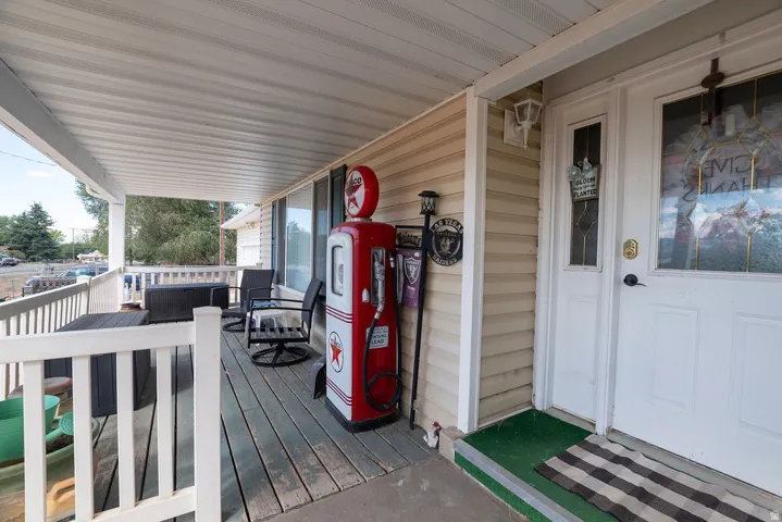 Covered porch with wood-finish decking, white railings, and siding exterior