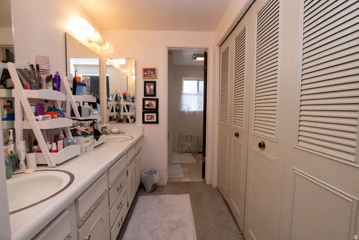 Dual vanity with integrated sinks, expansive counter space, wall-mounted mirrors, and built-in storage cabinetry