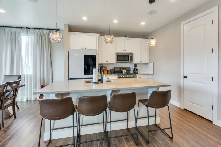 Kitchen featuring white cabinetry, stainless steel appliances, a center island with countertop seating, and wood-finish flooring