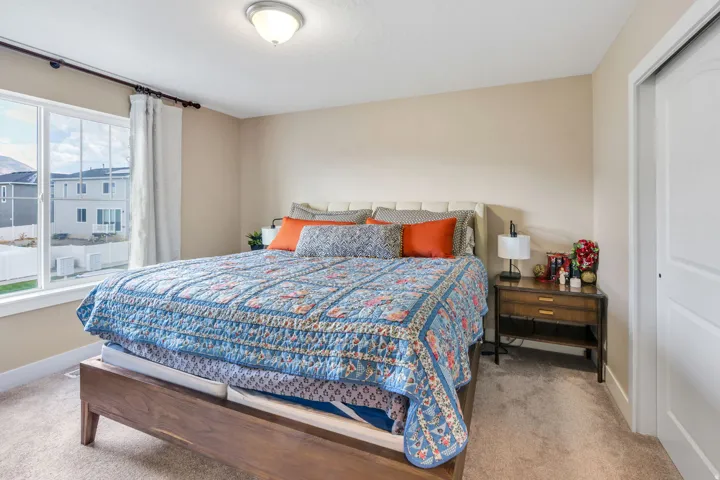 Neutral wall paint, carpeted flooring, a ceiling-mounted light fixture, a window with white trim, and a bi-fold closet door