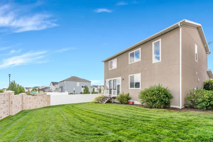 Rear exterior with stucco finish, multiple windows, sliding glass door, and a white privacy fence