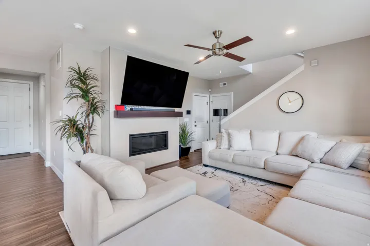 Recessed lighting, wood-finish flooring, a contemporary fireplace, and a ceiling fan with wood-finish blades
