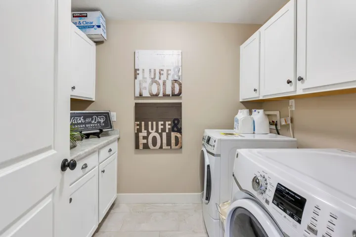 Laundry area featuring white cabinetry, a solid surface countertop, and tile flooring