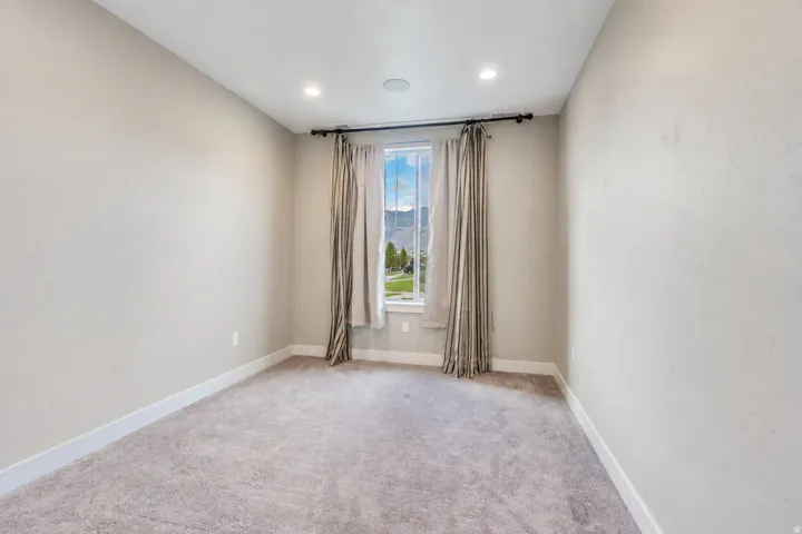 Recessed lighting and ceiling speaker feature in this carpeted room with a window and mountain scenery