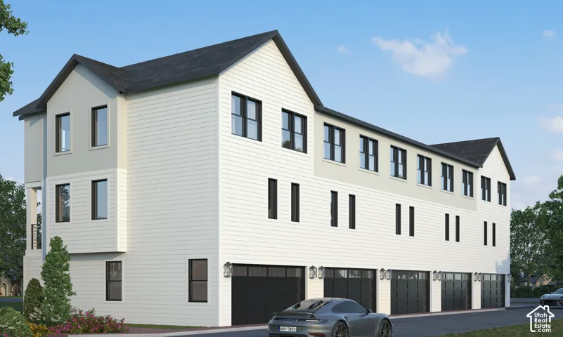 Multi-story townhome with light-colored siding, black-framed windows, and multiple individual garages