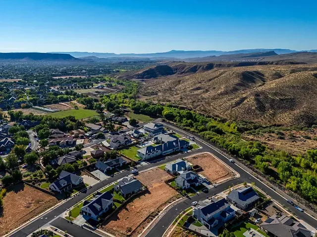 Expansive mountain and valley scenery, established residential areas, new construction plots, paved roadways, and natural green spaces