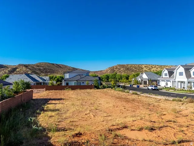 Expansive vacant land parcel featuring a clear building site, perimeter block wall, and paved street frontage