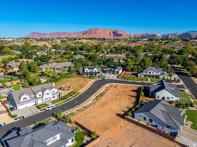 Expansive undeveloped land parcel with surrounding residential properties and mountainous backdrop