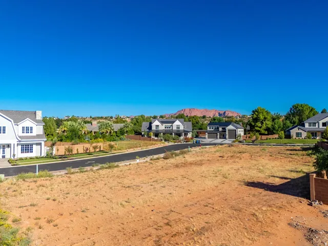 Expansive undeveloped lot with surrounding residential properties and distant red rock formations