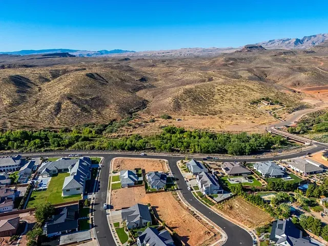Expansive residential development featuring paved streets and established homes, set against a backdrop of natural desert hills and distant mountains