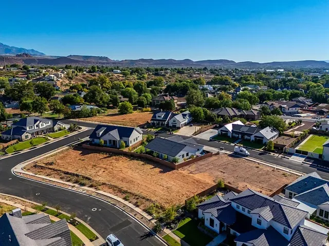 Expansive undeveloped lots within a residential neighborhood featuring paved streets and surrounding homes