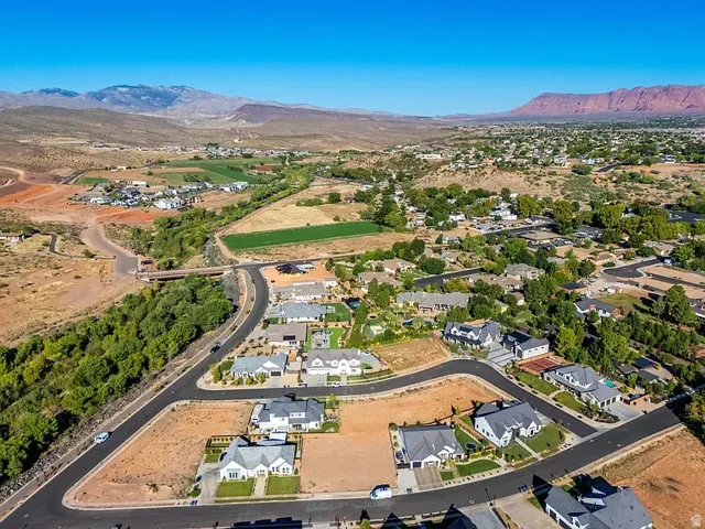 Developed neighborhood with paved roads, surrounding green spaces, and distant mountains
