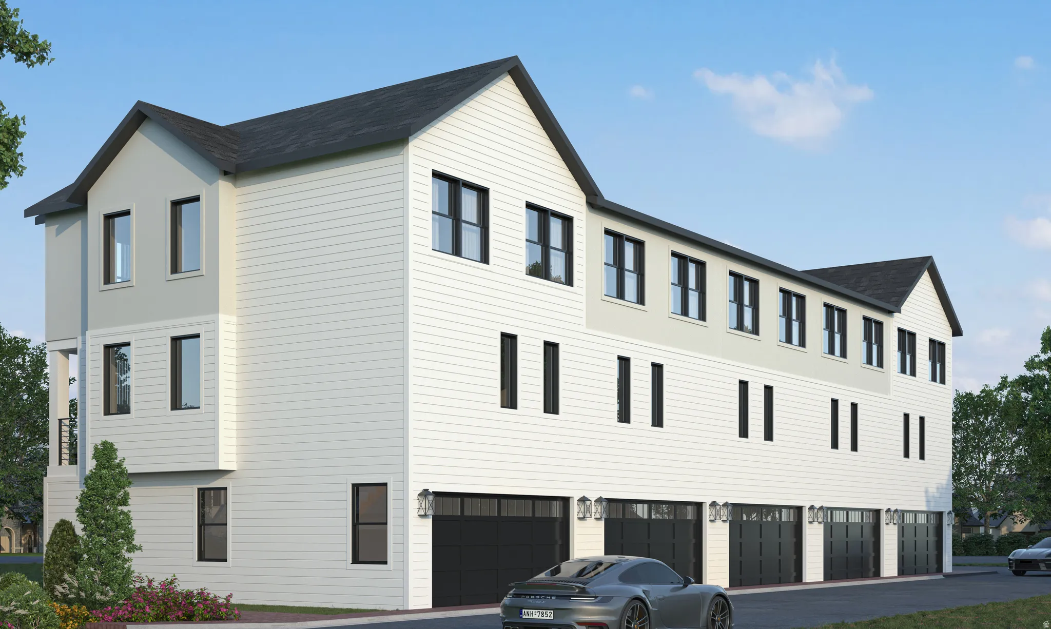 Multi-story townhome with light-colored siding, black-framed windows, and multiple individual garages