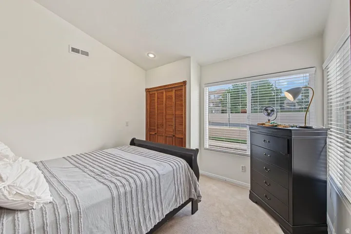 Recessed ceiling lighting, wood-finish bi-fold closet doors, wall-to-wall carpeting, and a large window with blinds