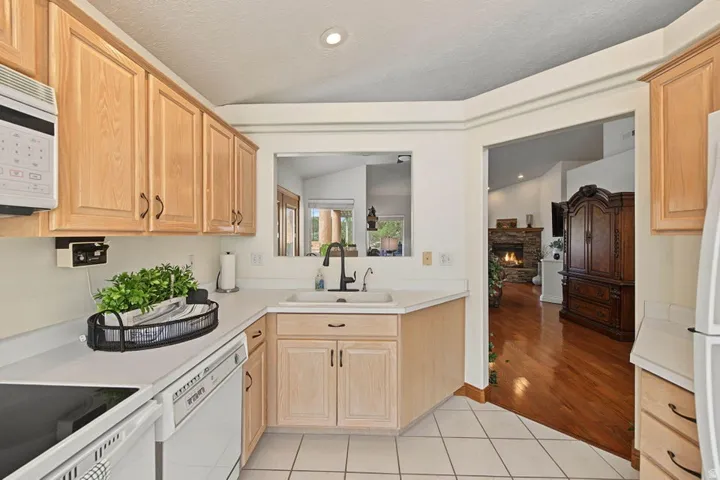 Kitchen featuring light wood cabinetry, white countertops, a built-in microwave, and a pass-through window