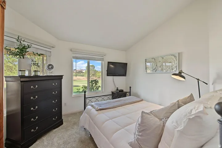 Room with vaulted ceiling, two windows, and light-colored carpet
