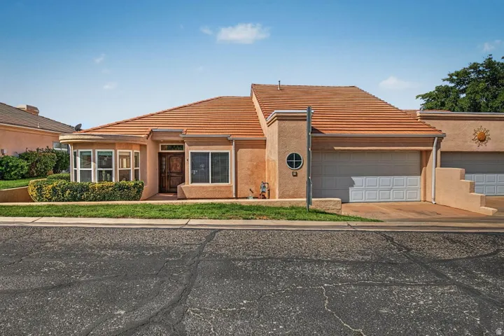 Stucco exterior with a terracotta tile roof, bay window, and an attached two-car garage