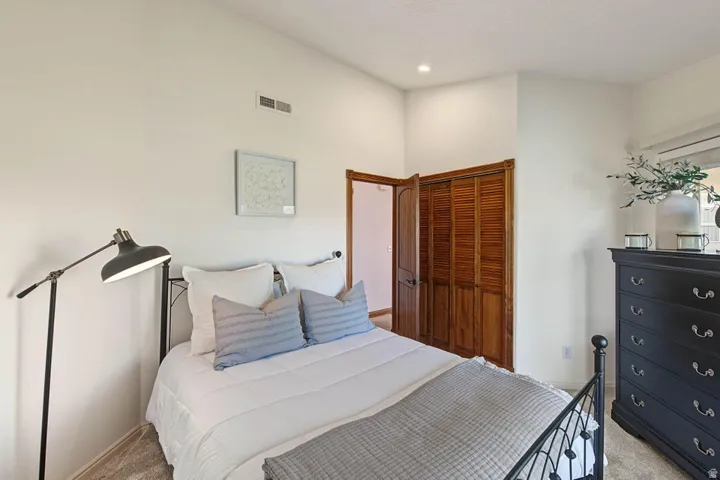 Vaulted ceilings with recessed lighting, wood louvered closet doors, and light-toned wall finishes