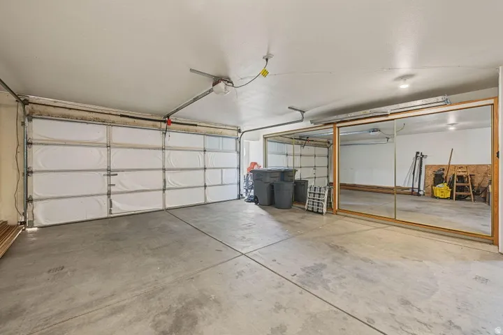 Garage space featuring a concrete floor, an overhead garage door, and mirrored sliding doors