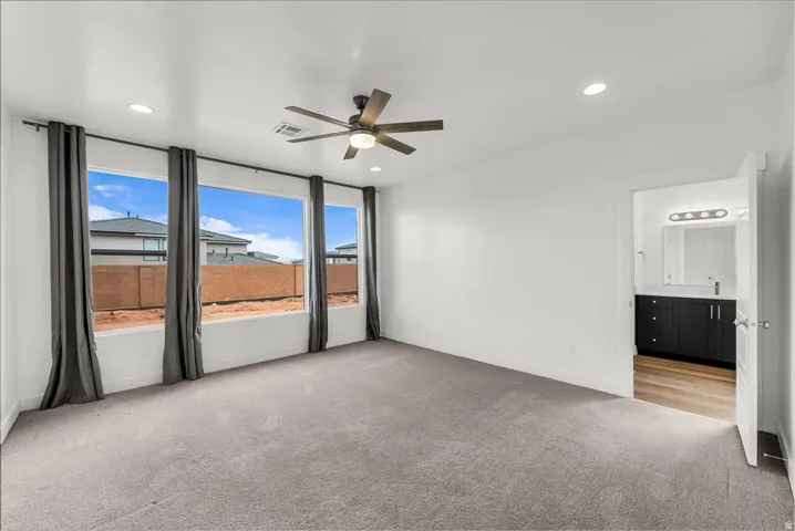 Expansive room featuring three large windows, a ceiling fan with integrated lighting, and recessed ceiling lights
