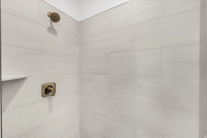 Shower with light-toned horizontal wall tiles, built-in shelf, and bronze-finish fixtures