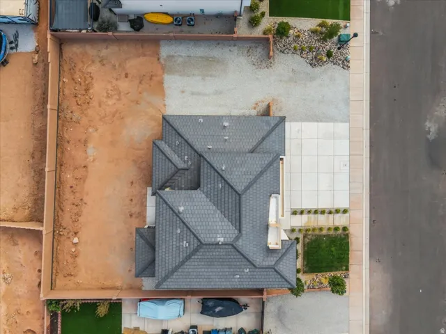 Pitched shingle roof with multiple gables, extensive undeveloped lot space, paved driveway, concrete walkways, and a landscaped front yard with artificial turf