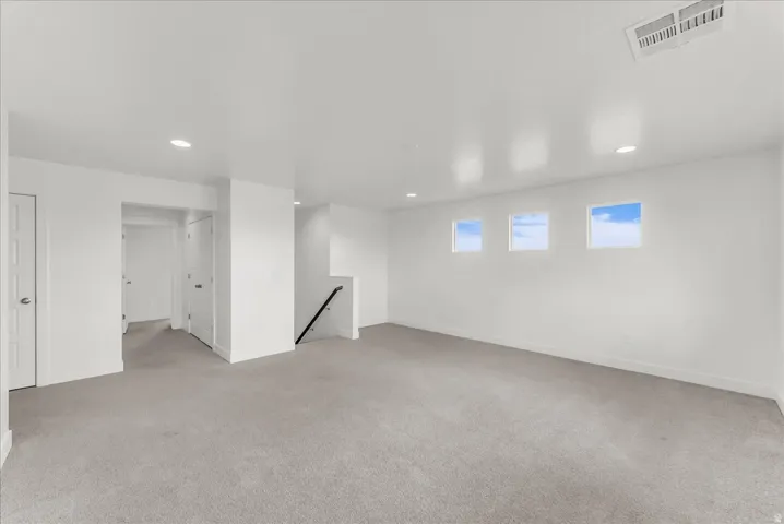 Recessed lighting, wall-to-wall carpeting, three transom windows, a built-in stairwell, and a crisp white color palette