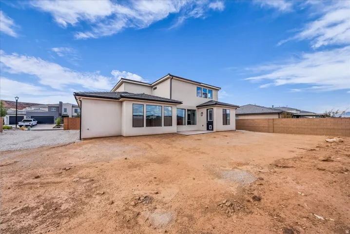 Contemporary stucco exterior with a multi-pane window array, second-story fenestration, rear patio, and a block perimeter wall