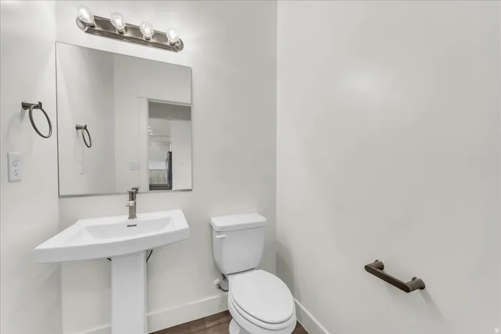Pedestal sink with a brushed nickel faucet, large wall mirror, and a four-bulb vanity light fixture