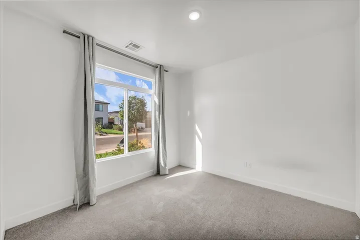 Recessed lighting, large window, clean carpet flooring, white walls, and white trim
