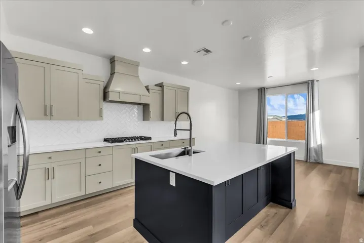 Modern kitchen featuring an expansive center island with an undermount sink, light wood-finish flooring, recessed lighting, and a window with a mountain backdrop