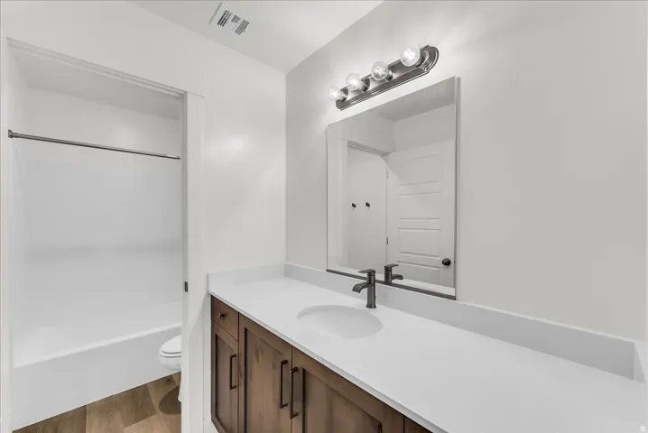 Spacious vanity with a white countertop and rectangular undermount sink, dark wood-finish cabinetry, and a dark-finish faucet