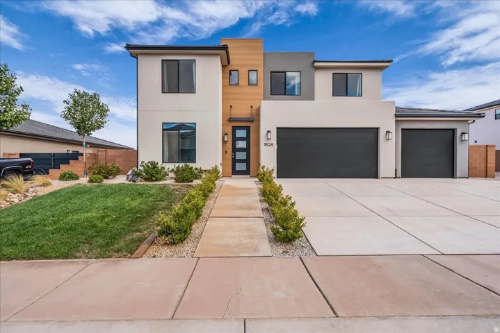 Modern architectural design featuring varied exterior finishes, an attached two-car garage, a separate single-car garage, and a concrete driveway