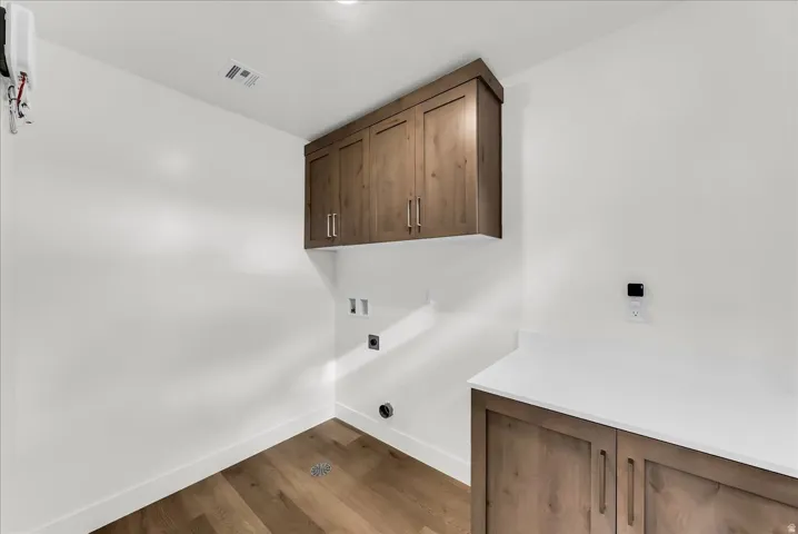 Wood-finish flooring, white walls, and wood-finish cabinetry with silver hardware