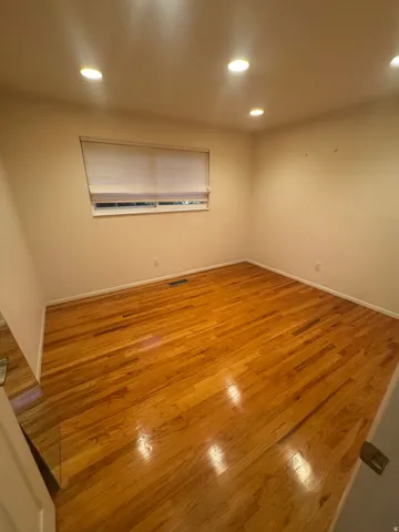 Wood-finish flooring with baseboard trim, recessed lighting, and a window with blinds