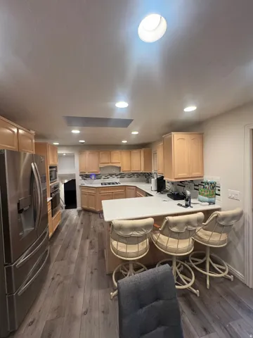 Kitchen featuring wood-finish flooring, recessed lighting, light wood cabinetry, and stainless steel appliances