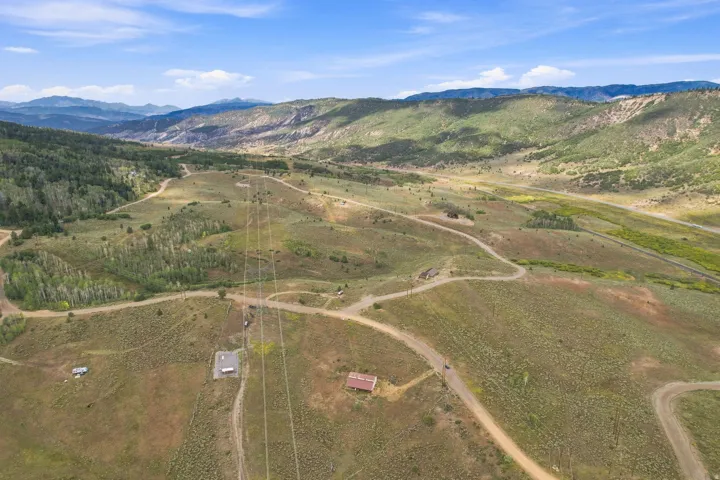Expansive land featuring rolling hills, scattered trees, and distant mountains