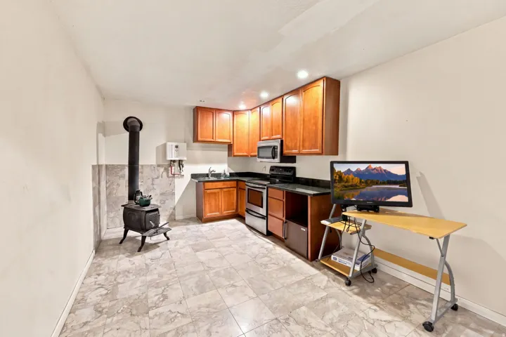 Kitchenette featuring wood cabinetry, stainless steel appliances, dark countertops, and recessed lighting